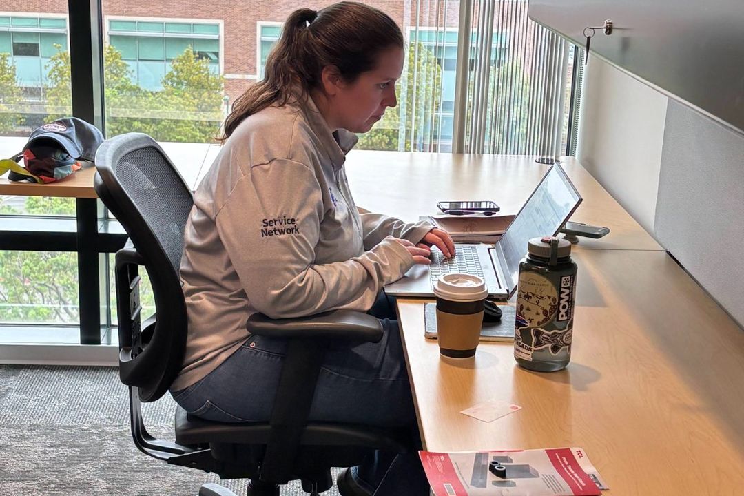 A Rust team member in a Service Network jacket working at a laptop in the Irvine, California office